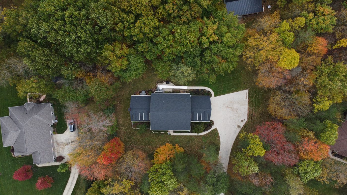 Top-down aerial drone photo of a completed shingle roof framed by autumn trees in Northeast Ohio