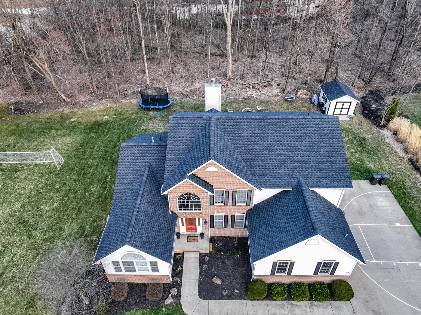 Aerial drone photo of a completed charcoal shingle roof on a brick and white-sided Northeast Ohio home